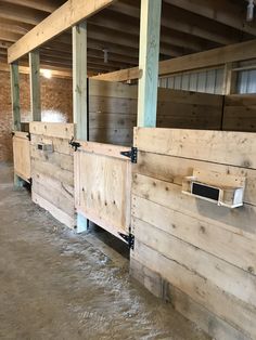 the inside of a horse barn with wooden stalls