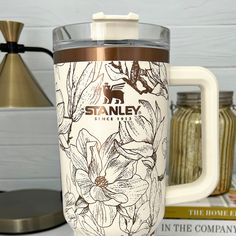 a coffee mug sitting on top of a table next to some books and a lamp