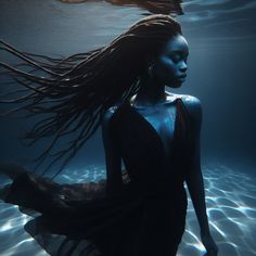 a woman with long hair standing under water in the ocean, wearing a black dress