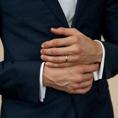 a man in a suit with his hands on his chest and wearing a wedding ring