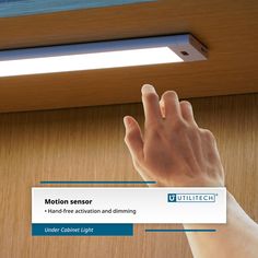 a hand reaching up to touch the ceiling light on a wooden paneled surface with text below that reads motion sensor - hand free action and dimming under cabinet light