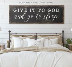 a bed with white sheets and pillows in front of a sign that says give it to god and go to sleep