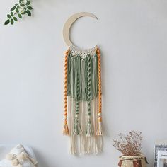 a wall hanging with tassels on it and a crescent shaped object in the background