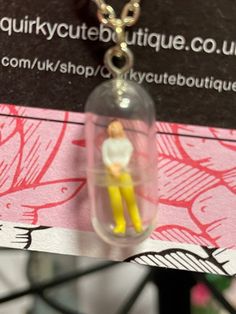 a small doll in a tiny glass jar on a chain with a keychain attached to it