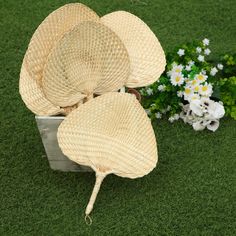 three straw hats sitting on top of a green field next to white and yellow flowers