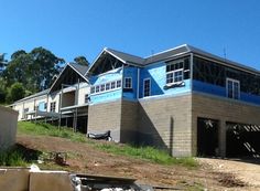 a house under construction with blue paint on the roof and windows in the building next to it