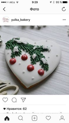 a heart shaped cookie decorated with holly and cherries on top of a white table