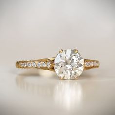 a close up view of a diamond ring on a white surface with the center stone in yellow gold