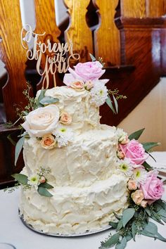 a white wedding cake with pink flowers and greenery