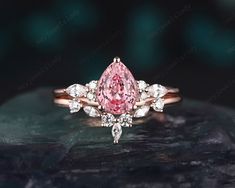 a pink and white diamond ring on top of a rock