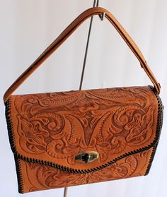 Vintage 1950's hand-tooled leather handbag with leather strap for using as a crossbody . Exquisite floral design on both sides. Pretty brass clasp works smoothly. Black Lining.  It measures 9-1/4 in x 7 1/2 in x 3 in. Excellent vintage condition. Tooled Leather Handbags, Vintage Tools, Hand Tooled Leather, Tooled Leather, Leather Tooling, Leather Handbag, Cross Body Handbags, Purses And Handbags, Leather Handbags