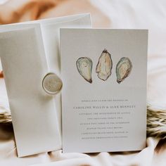 a wedding card with two seashells on it and a ring in the middle