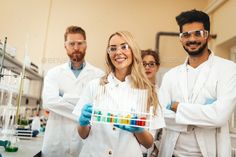 three people in lab coats holding test tubes and smiling at the camera - stock photo - images