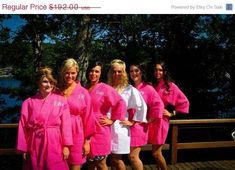 a group of women in pink robes standing on a deck next to trees and water