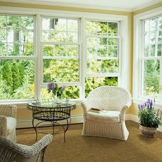 a living room with wicker furniture and large windows that look out onto the trees