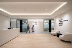 an office lobby with two white chairs and a reception desk in front of the wall