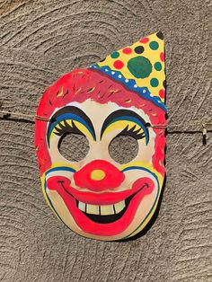 a clown mask hanging on the side of a wooden wall