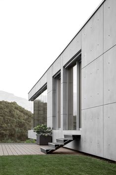 an exterior view of a modern house with grass and stairs leading to the front door