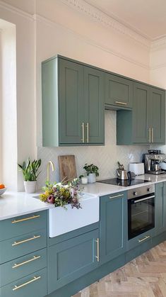 a kitchen with green cabinets and white counter tops, wood flooring and wooden floors