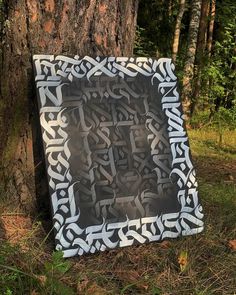 a black and white painting sitting on the ground next to a tree