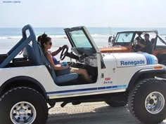 a woman sitting in the driver's seat of a white jeep on the beach