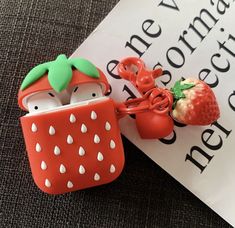 an apple and strawberry cell phone case sitting on top of a book