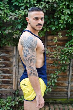 a man with a dragon tattoo on his arm standing in front of a wooden fence