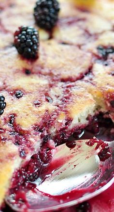 a close up of a pie with berries on it and a spoon in the foreground