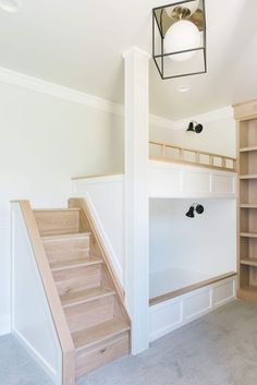 an empty room with white walls and wooden steps leading up to the second floor area