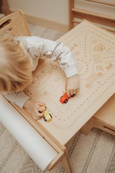 a little boy playing with toys on a wooden table