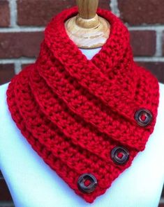 a red knitted cowl with buttons is on top of a mannequin