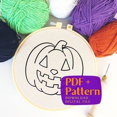 an embroidery project with pumpkins and balls of yarn next to it on a white surface