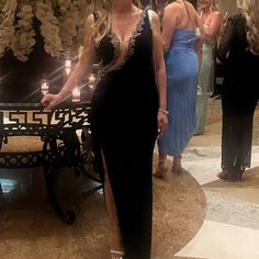 a woman in a long black dress standing next to a table with candles on it