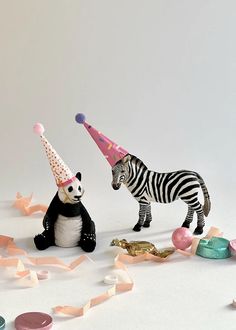 two toy zebras wearing party hats and confetti