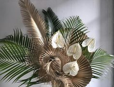 a vase filled with lots of white flowers on top of a wooden table next to a wall