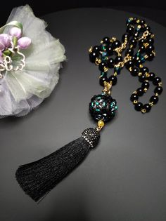 Beautiful sautoir necklace with long tassel. The main elements of this necklace are two: a large 30 mm pearl covered in beads and crystals and a splendid black tassel with Marcasite. These crystals give a lot of brightness and make the necklace very elegant. The pearl is covered by hand with different types of beads, a precision and difficult job to perform. The necklace is made with black agate beads of different sizes and crystals. Some points are highlighted with the beautiful emerald green color which gives a mystical look to the necklace. Everything matches perfectly, colors and shapes. The closure is an 18K gold-plated opening ring. The pendant with the ball and the tassel can be removed if desired and you can only wear the simple necklace. The necklace is very elegant, perfect for l Elegant Necklace With 108 Beads For Gift, Elegant Necklace With 108 Beads Pendant, Elegant Necklace With 108 Beads For Party, Elegant Party Necklace With 108 Beads, Long Necklace With Black Round Beads For Gift, Elegant Handmade Tassel Necklace With Round Beads, Long Necklace With Black Beads As Gift, Long Necklace With Round Black Beads As Gift, Elegant Party Necklace With 8mm Beads