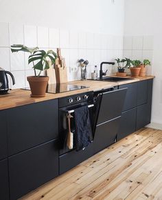 a kitchen with wooden floors and black cabinets