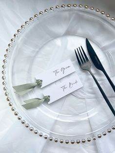 two forks and one knife on a white plate with silver beaded trimmings