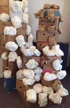 cardboard boxes stacked on top of each other in the middle of a room with white bags