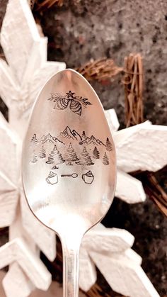 a spoon with drawings on it sitting in front of snowflakes and branches,