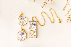 three necklaces with flowers on them sitting next to each other and one is hanging from a gold chain