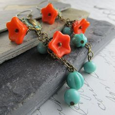 "Bright orange glass flowers and vintage turqoise beads dangle in shabby chic style from delicate roses. For extra charm, the roses have been finished with a pretty verdigris patina and hang from handcrafted antique brass French earwires. Some of the flowers are more of a red/orange, than orange. If you prefer one or the other, please leave me a note in \"message to seller\" at checkout. Length: 2 1/8\"(63mm) from bottom loop of french earwire Prefer a different style of earwire? Leverbacks and