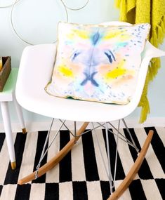 a white rocking chair with a colorful pillow on it