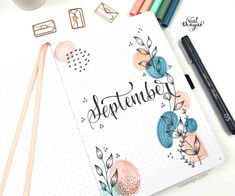 a notebook with the word september written on it next to some markers and pencils