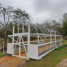 a large white structure sitting on top of a lush green field next to a forest