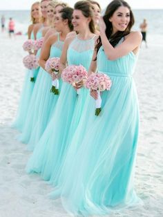 a group of women standing on top of a beach next to each other holding bouquets