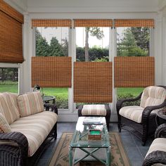 a living room filled with furniture and windows covered in bamboo blind shades on top of them