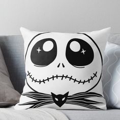 a white pillow with black eyes and a cat's head on it, sitting on a couch