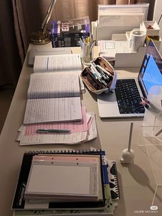 an office desk with several notebooks, papers and laptop computers sitting on top of it