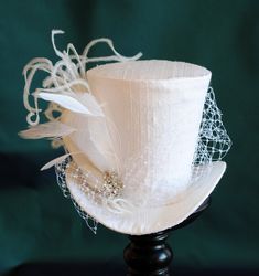 This simple and elegant bridal mini top hat is covered with beautiful white silk shantung. It is embellished with white veil, a luxurious spray of curled ostrich plums and a sparkling flower shaped rhinestone button. Also available in ivory and black here : https://www.etsy.com/shop/BizarreNoir?ref=seller-platform-mcnav&section_id=14329940 If you're interested in another color, please, send me a message to talk about your options. This mini top hat is fully lined with satin and attaches to t White Top Hat, Bridal Mini, Ivory Fascinator, Hat With Veil, White Fascinator, White Veil, White Cocktails, White Victorian, Mad Hatter Hats